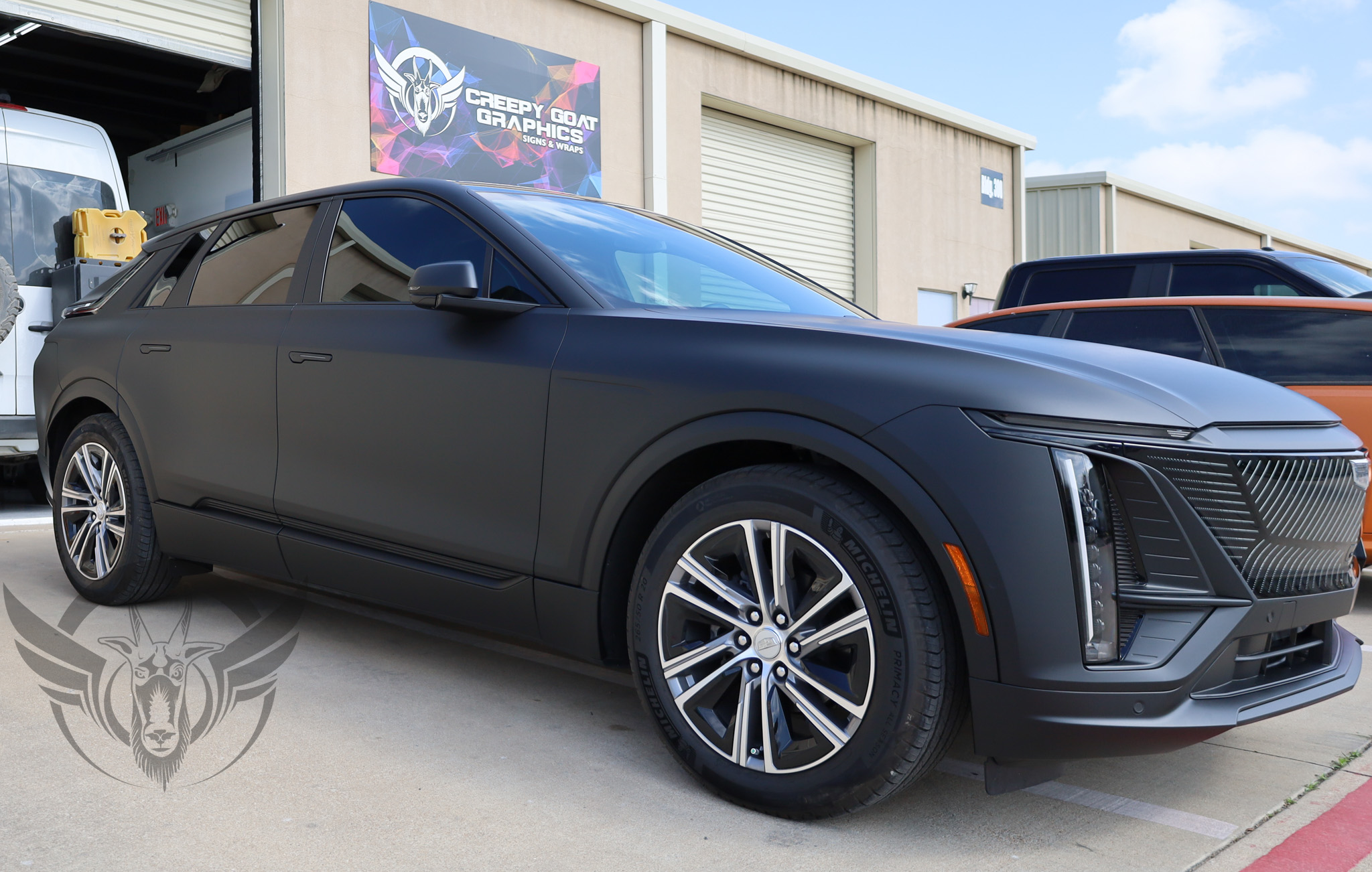 A Cadillac Lyric wrapped in matte black parked in front of Creepy Goat Graphics wrap shop