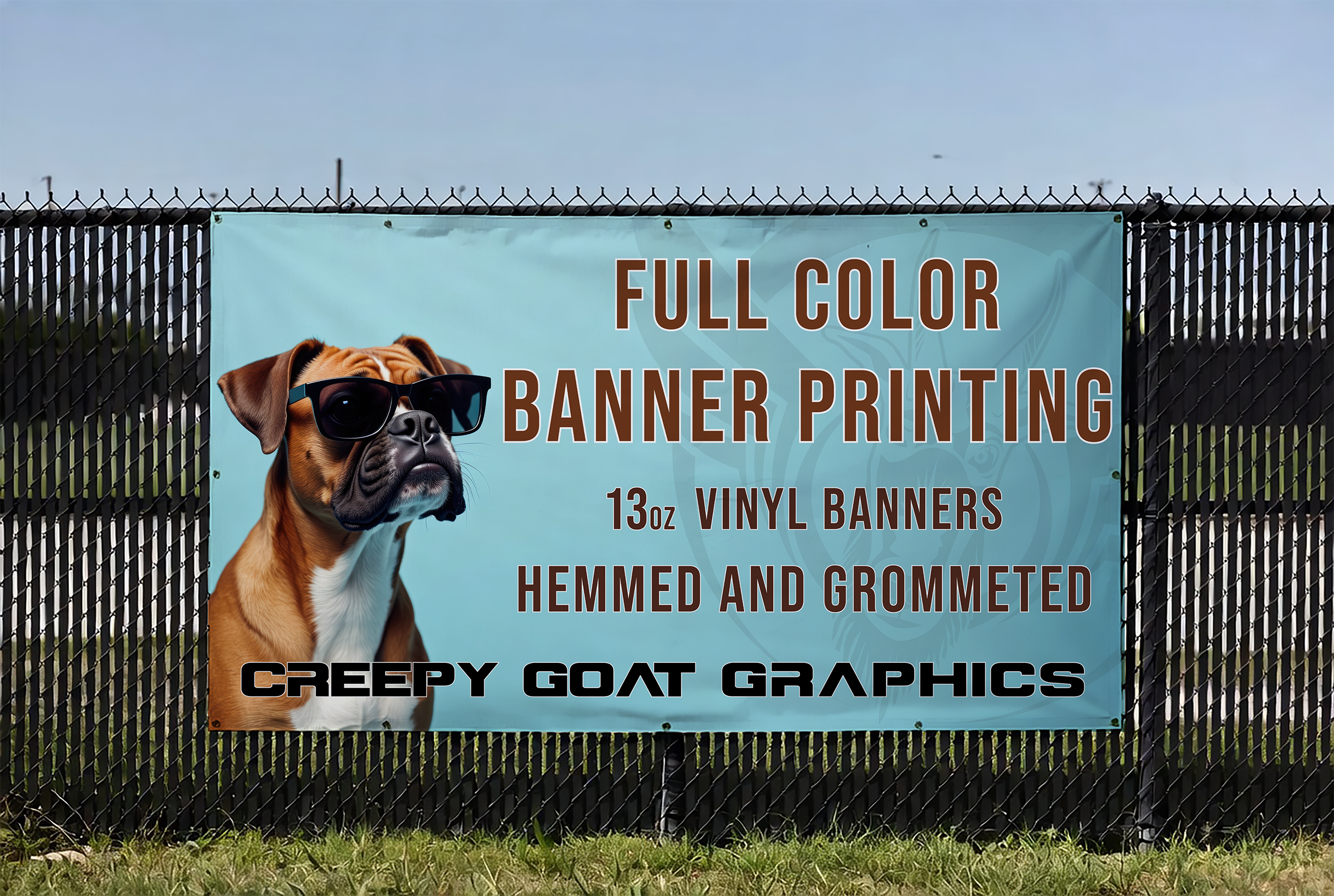 A printed banner displayed hanging on a fence, with graphics by Creepy Goat Graphics