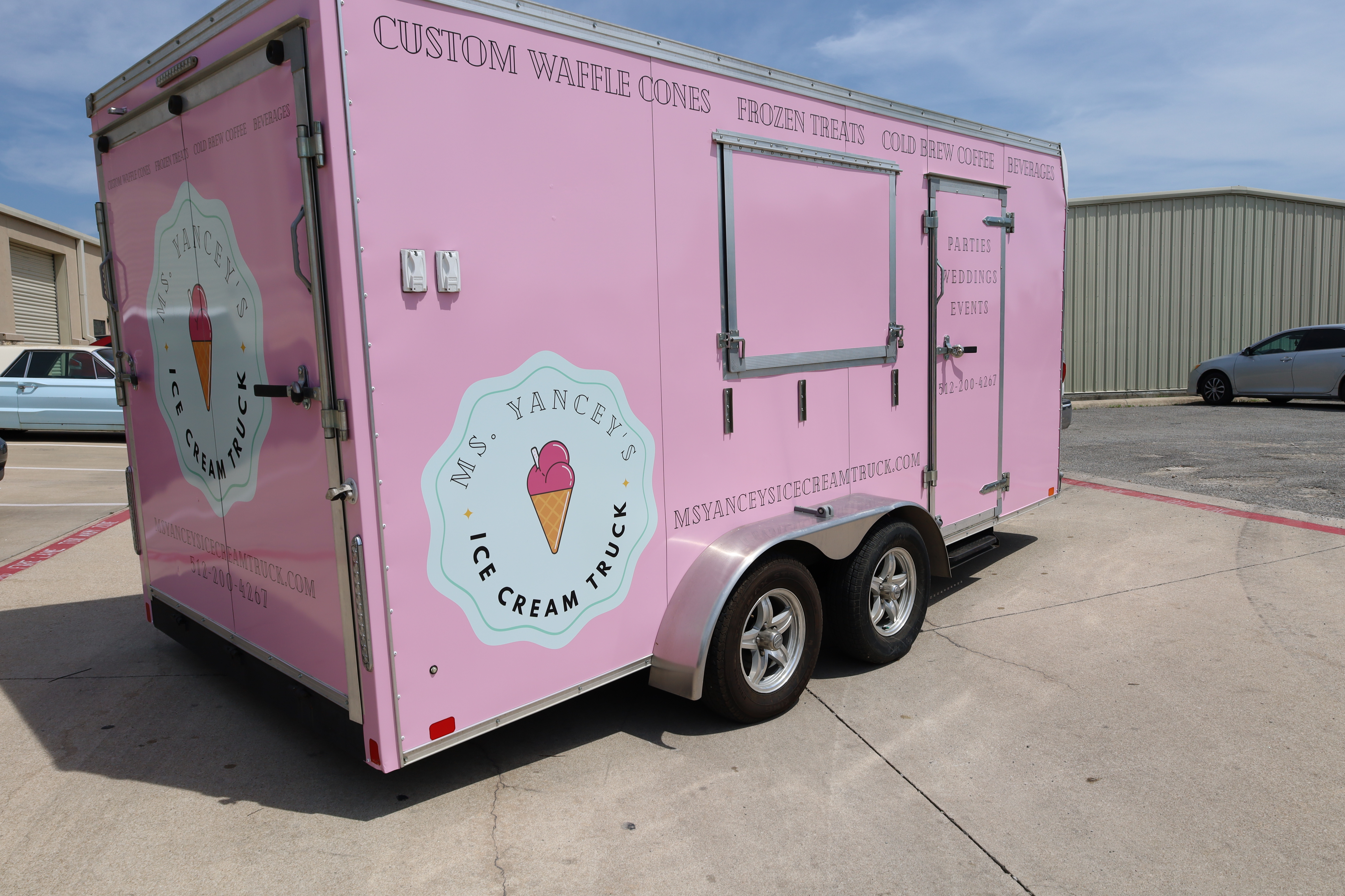 An ice cream food trailer wrapped in pink with logo and information