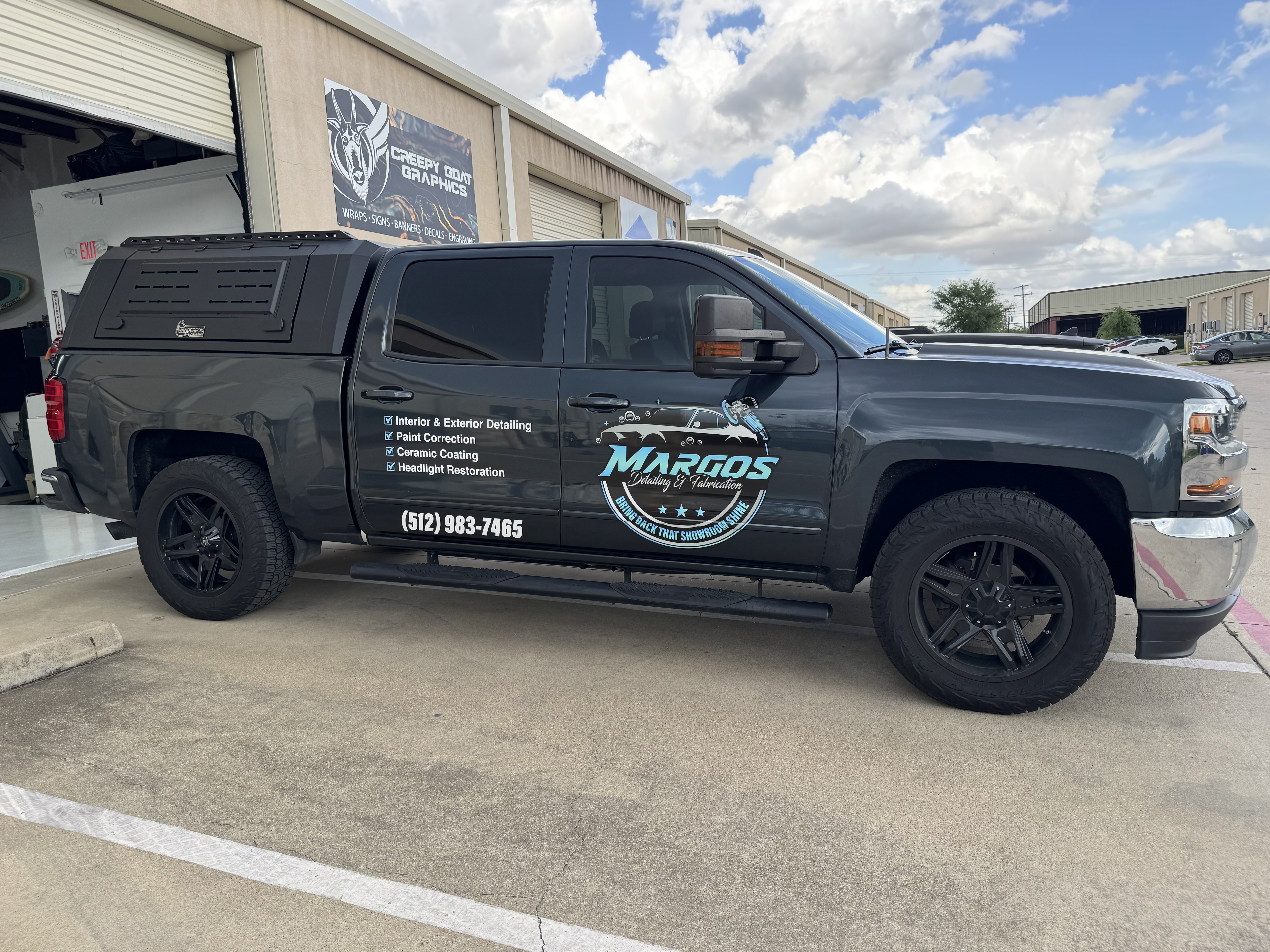A chevy truck with vinyl lettering applied to, displaying Margos Detailing.  Sitting in front of Creepy Goat Graphics Sign and Wrap Shop 